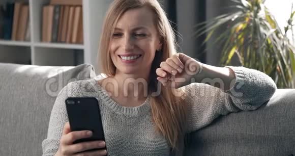 女人坐在沙发上在视频聊天中挥手视频的预览图