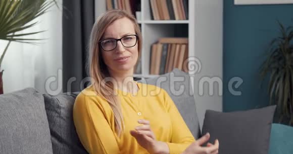 穿黄色毛衣和眼镜的女人坐在沙发上视频的预览图