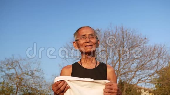 快乐老人在公园锻炼后用白毛巾擦汗保健概念视频的预览图