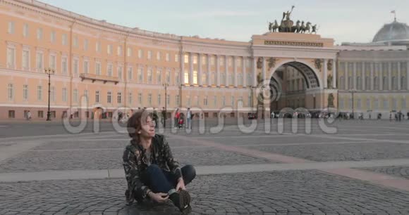 这位美丽的年轻人坐在皇宫广场上日落时分喝咖啡他穿着一件军服视频的预览图