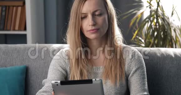 微笑的女人坐在沙发上拿着数码小玩意视频的预览图