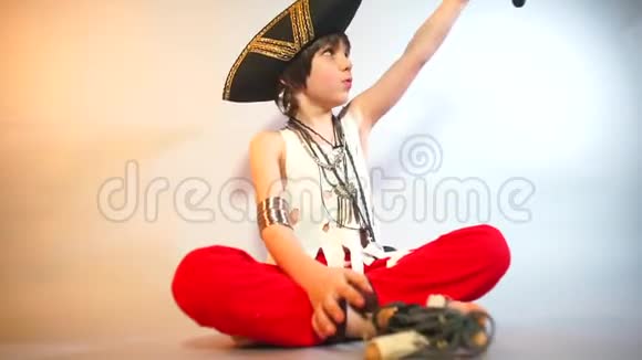 一个穿着海盗服装的孩子在浅色背景上和洋娃娃海盗摆姿势视频的预览图