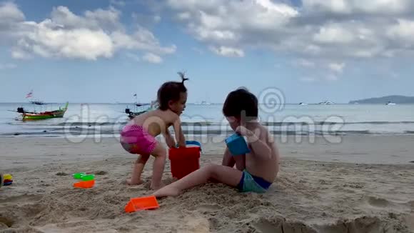 快乐的孩子们在阴天的海滩上玩玩具和沙子视频的预览图