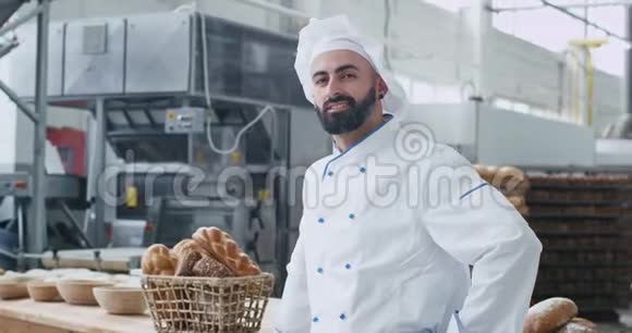 在一家商业厨房的面包店里一位有魅力的面包师男子胡子笑得很漂亮视频的预览图