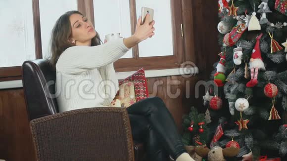 女孩坐在圣诞树附近自拍视频的预览图