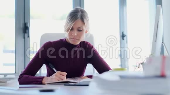 年轻的女商人在办公室工作时专心做笔记视频的预览图