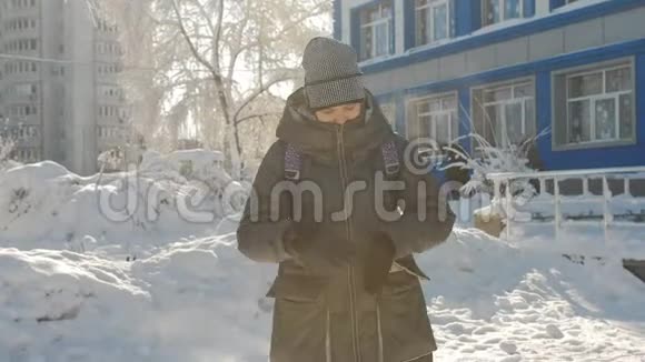 一个十几岁的女孩在学校大楼附近等待你的朋友在冬天视频的预览图