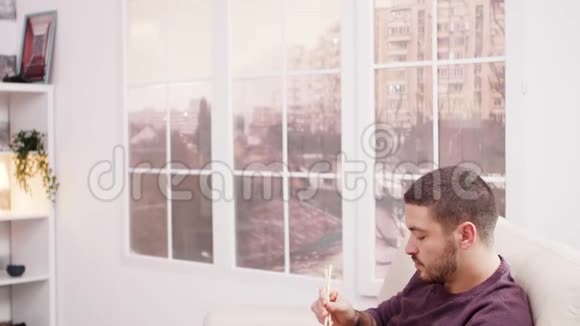 一个蓄着胡子的男人正在享受一盒中国面条视频的预览图