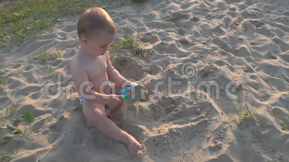 小男孩坐在沙子里玩水桶和铲子视频的预览图
