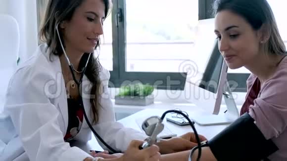 年轻漂亮的妇科医生在诊所检查她怀孕病人的血压视频的预览图