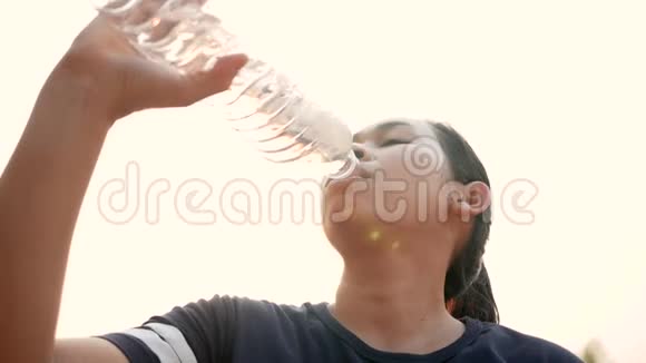亚洲年轻妇女在公园慢跑后从塑料瓶里喝水减肥健康的生活方式观念视频的预览图