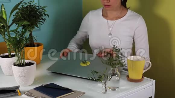 年轻女子在绿色植物周围的办公室里打开她的笔记本电脑视频的预览图