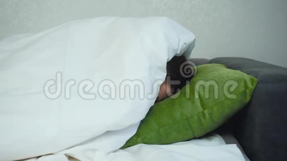 男人躺在床上从毯子下面往外看然后躲起来他头躺在枕头上奇怪视频的预览图