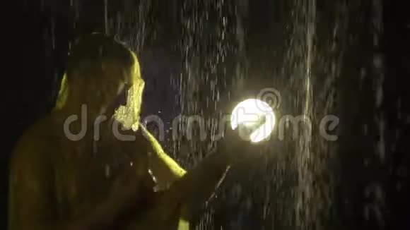 穿着雨衣的人手里拿着扫帚好像在雨中弹吉他一个黄色的光滑的像岩石一样的贝森视频的预览图