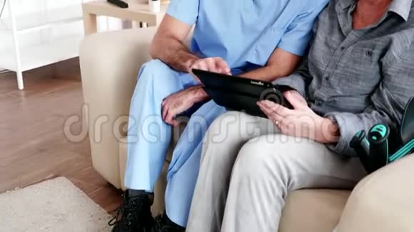 男护士教老年妇女如何使用她的平板电脑视频的预览图