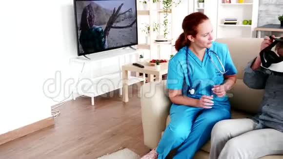 女性照顾者帮助老年妇女在养老院体验虚拟现实视频的预览图