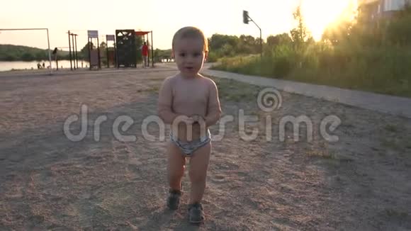 一个穿着游泳短裤手里拿着球锥的男孩在夕阳下微笑视频的预览图