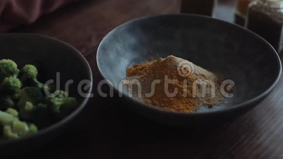 在厨房的桌子上放着一个碗里面有香料和西兰花的混合物用来准备健康的食物特写视频的预览图