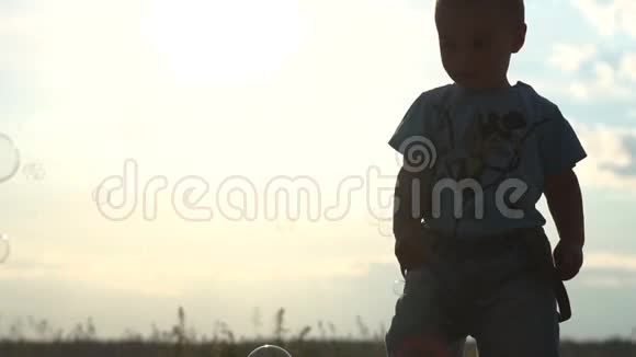 可爱的小男孩和肥皂泡在日落时慢动作视频的预览图