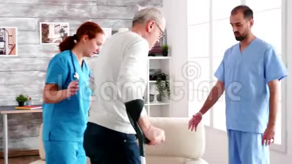 老人拄着拐杖由年轻的男医生和女医生帮助视频的预览图