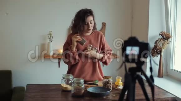 一个年轻的女孩切蔬菜在相机上谈论香料写一篇关于食物的博客视频的预览图