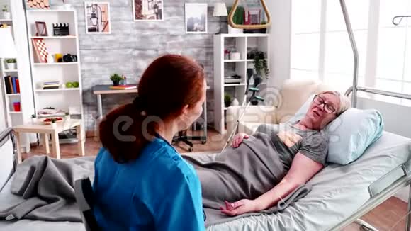 女性医护人员抱着躺在病床上的老妇人视频的预览图