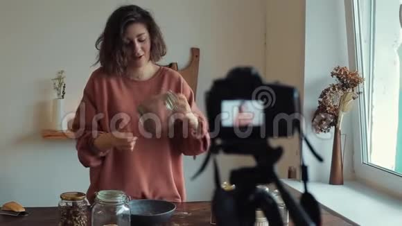 可爱的女性食品博主在镜头前谈论食物吃罐子里的坚果视频的预览图
