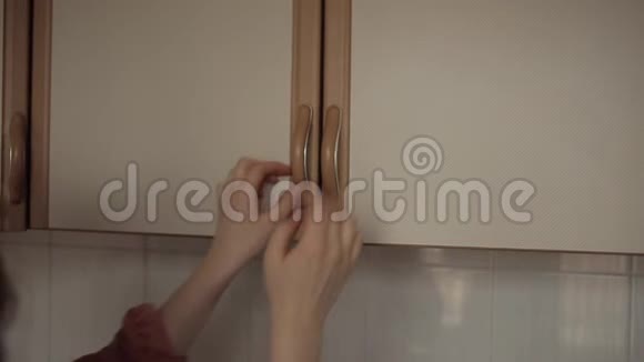 年轻漂亮的女孩从厨房橱柜的架子上拿出一罐坚果微笑着吃视频的预览图