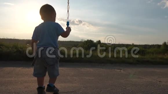 可爱的小金发男孩和肥皂泡在日落时慢动作视频的预览图