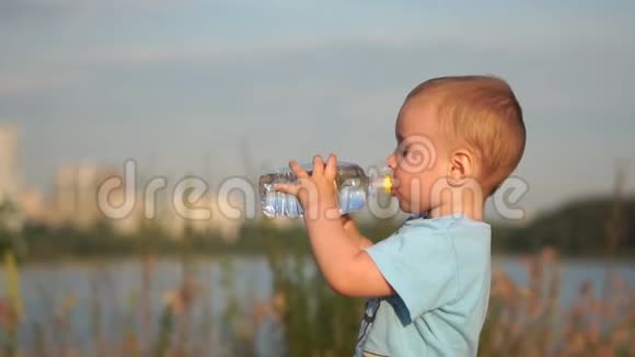 小金发男孩在日落时缓慢地喝水视频的预览图