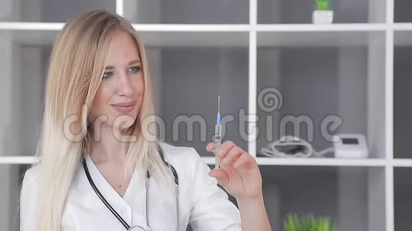 医生一位相貌出众的女士手里拿着一个注射器从注射器中释放出多余的空气看着视频的预览图