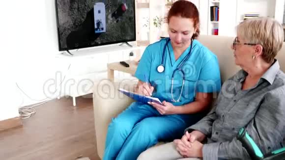 养老院护士在与老年退休妇女谈话时在剪贴板上记录笔记视频的预览图