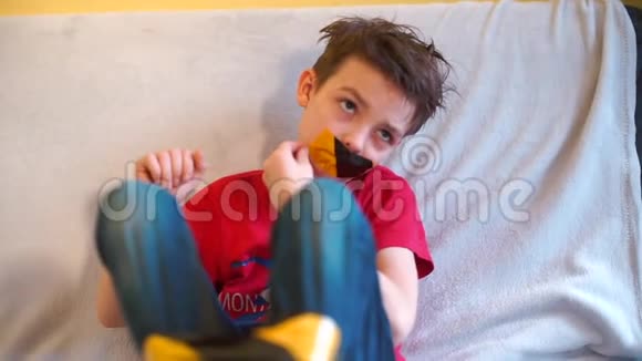 一个疲惫的孩子坐在沙发上从他的嘴里打开了一个掩盖胶带视频的预览图