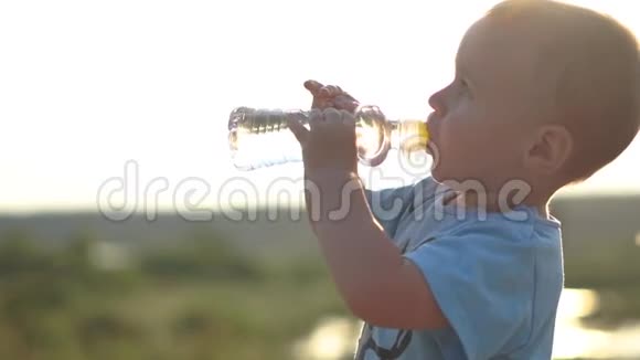 留着白发的小男孩在日落时缓慢地喝水视频的预览图