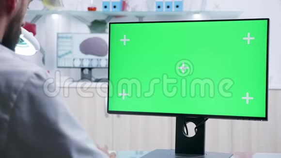 在绿色屏幕模拟电脑上工作的医生肩膀上的静态镜头视频的预览图
