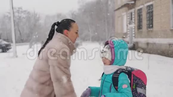 妈妈冬天穿着毛皮大衣放学后在学校大楼附近遇到一个小女孩视频的预览图