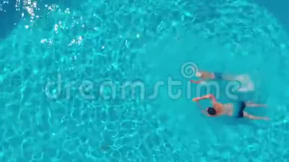 一个男人和一个男孩在一个开放的游泳池游泳的俯视图视频的预览图