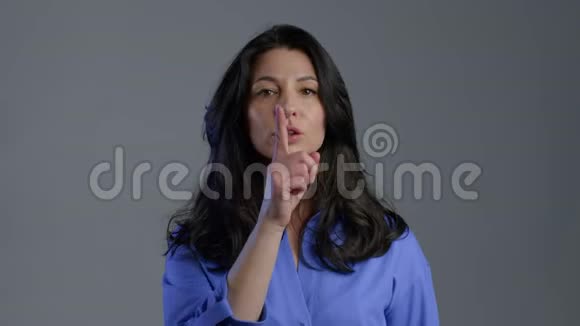严肃的女人长发手指在她的嘴唇上灰色的背景视频的预览图