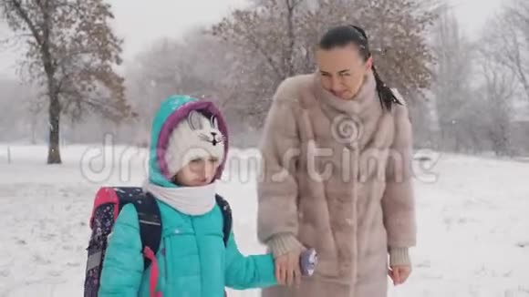 妈妈和小女儿在雪地里牵着手放学回家视频的预览图