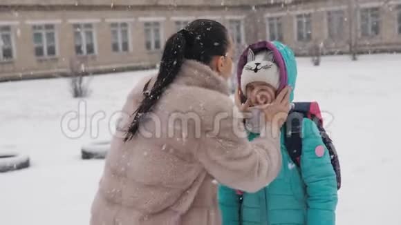 下雪了妈妈拥抱女儿在冬天步行去学校视频的预览图