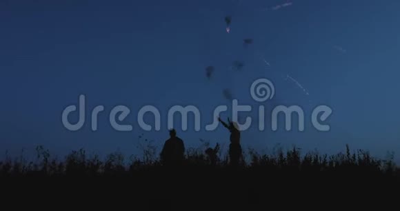 四口之家正欢快地跳着烟花在夏日的夜空中视频的预览图