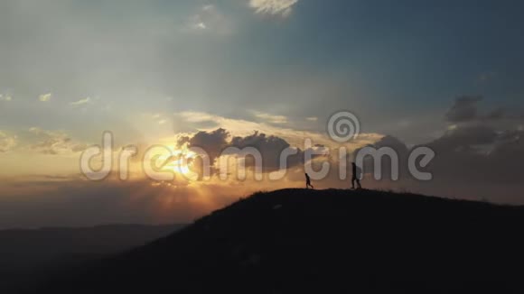 父子俩在美丽的夕阳下登上山顶视频的预览图