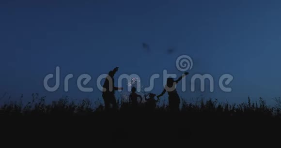 一个幸福的家庭用烟火在黑暗的天空上跳跃的缓慢动作视频的预览图