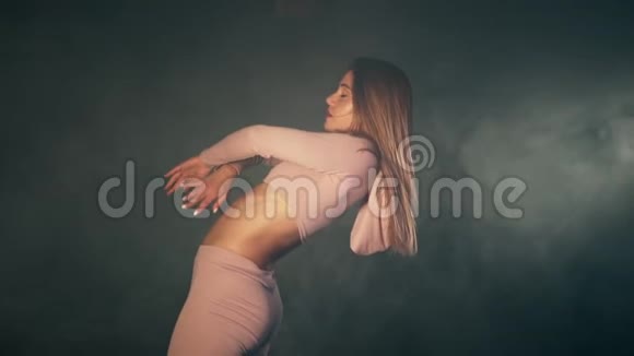 穿粉色紧身衣的女孩的肖像在黑暗的画室中尽情地跳舞视频的预览图