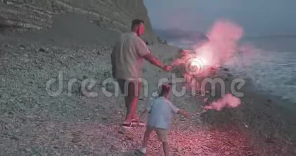 父亲和儿子在鹅卵石滩上放鞭炮视频的预览图