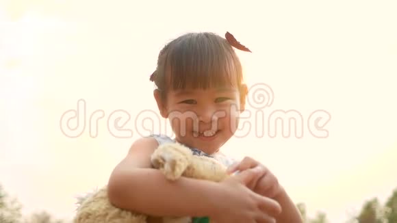 可爱的亚洲小女孩拥抱泰迪熊与感觉爱在公共公园视频的预览图