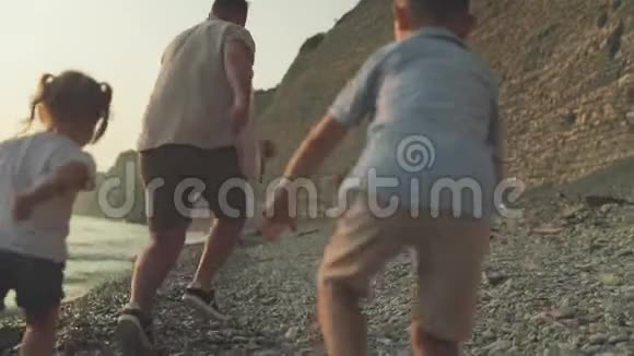 两个孩子玩着追逐父亲的慢动作视频的预览图