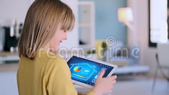 小女孩站在家里时使用带有数字平板电脑的domotic系统视频的预览图