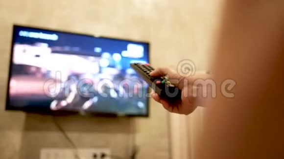 亚洲年轻女子在房间里看电视手里拿着遥控器调节音量或更换电视频道在l中放松视频的预览图