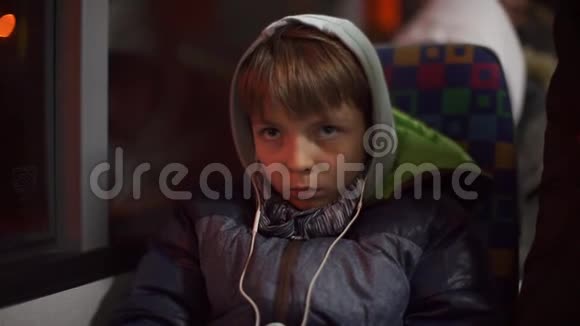 一个戴着耳机的青少年坐在公共交通巴士上的乘客座位上视频的预览图